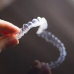 Closeup of hand holding Invisalign up
